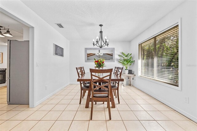 dining space featuring light tile patterned floors, a notable chandelier, and a textured ceiling