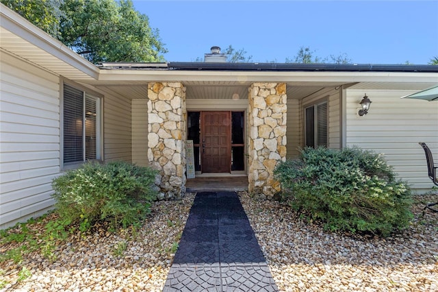 entrance to property featuring covered porch and a chimney