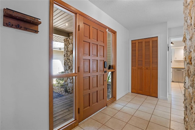 foyer with a textured ceiling and light tile patterned floors