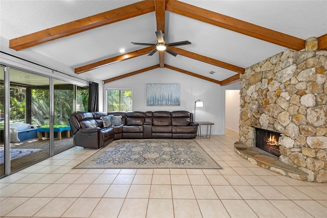 tiled living room with ceiling fan, a stone fireplace, and lofted ceiling with beams