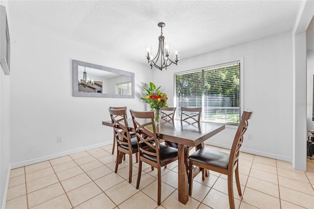 dining space featuring light tile patterned floors, a textured ceiling, baseboards, and an inviting chandelier