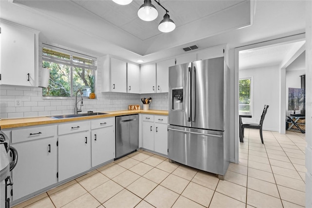 kitchen featuring stainless steel appliances, tasteful backsplash, a raised ceiling, visible vents, and a sink