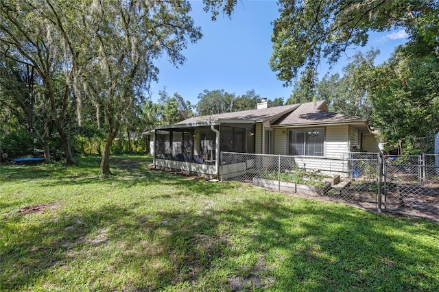 view of front of house with a sunroom, a chimney, a gate, fence, and a front yard