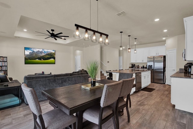 dining area featuring hardwood / wood-style floors, a raised ceiling, and ceiling fan