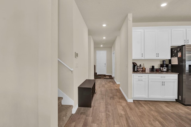 interior space featuring stainless steel refrigerator with ice dispenser, light hardwood / wood-style floors, and white cabinetry