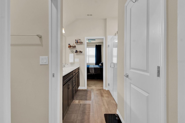 bathroom with hardwood / wood-style floors, vanity, and lofted ceiling