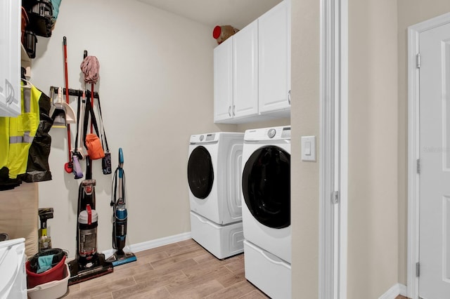 laundry room featuring separate washer and dryer, cabinets, and light wood-type flooring