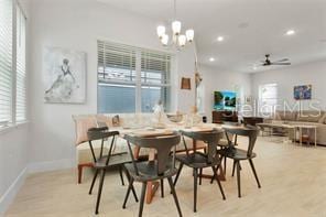 dining space with a healthy amount of sunlight, ceiling fan with notable chandelier, and light hardwood / wood-style floors