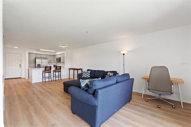 living room with a textured ceiling and light hardwood / wood-style flooring