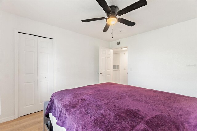 bedroom with light hardwood / wood-style flooring, ceiling fan, and a closet