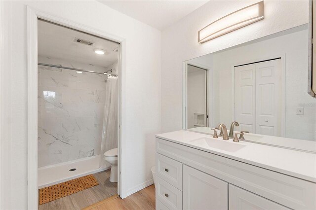 bathroom with vanity, toilet, curtained shower, and hardwood / wood-style floors