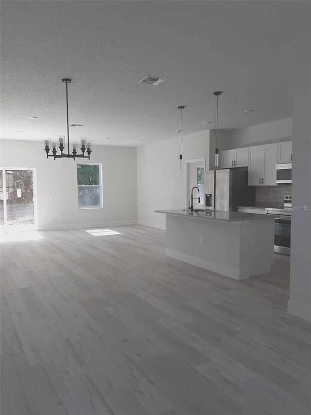 kitchen featuring white cabinetry, hanging light fixtures, a center island with sink, appliances with stainless steel finishes, and light hardwood / wood-style floors