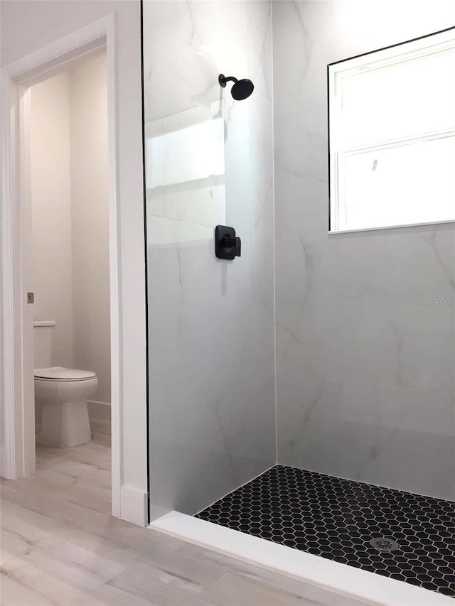 bathroom with a tile shower and toilet