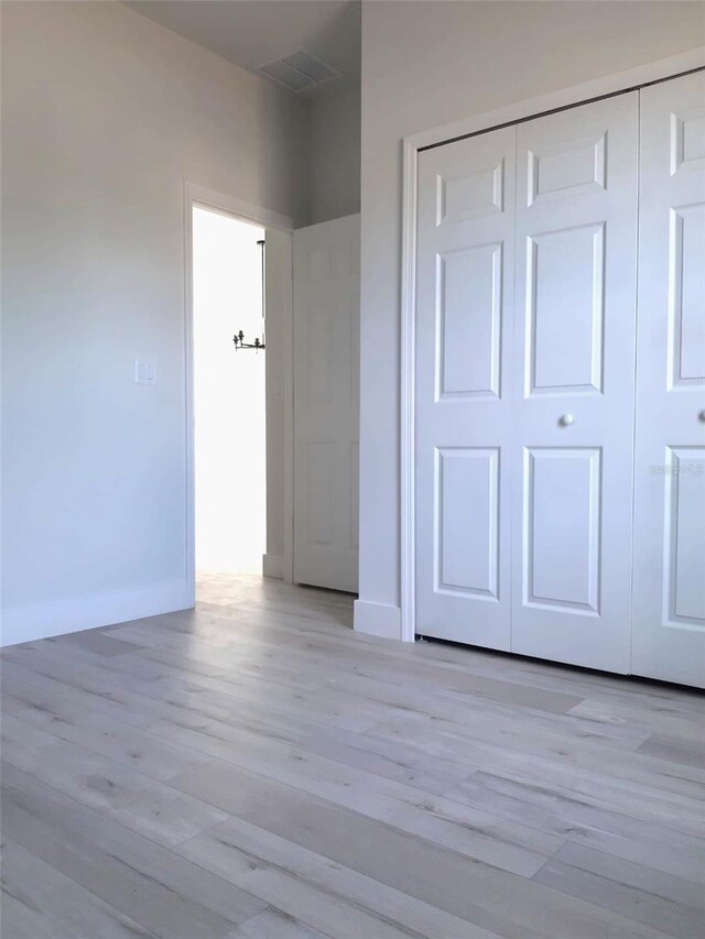 unfurnished bedroom featuring light hardwood / wood-style floors and a closet