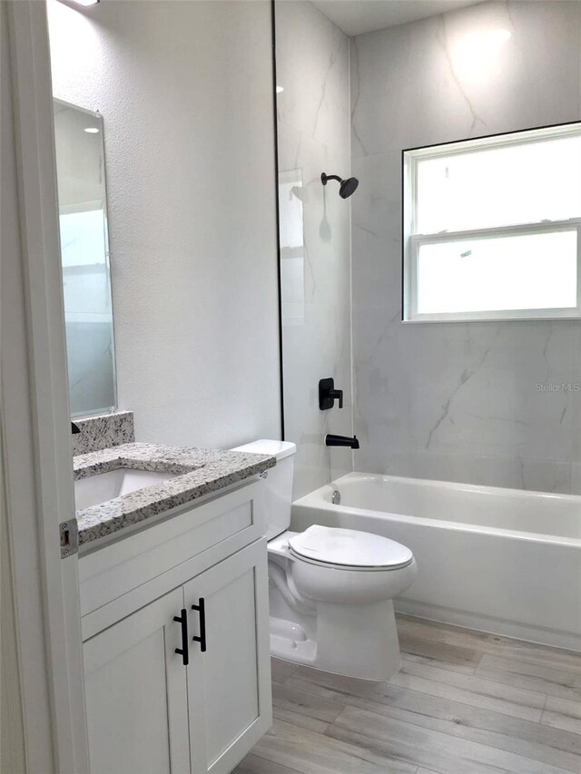 full bathroom featuring vanity, toilet, tiled shower / bath combo, and hardwood / wood-style floors