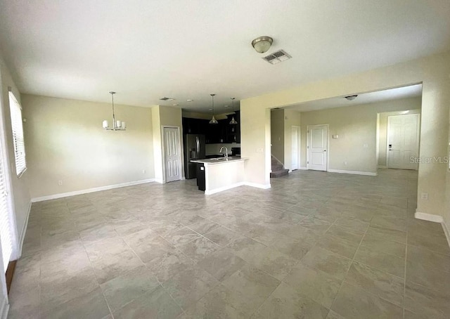 unfurnished living room with sink, an inviting chandelier, and light tile patterned floors