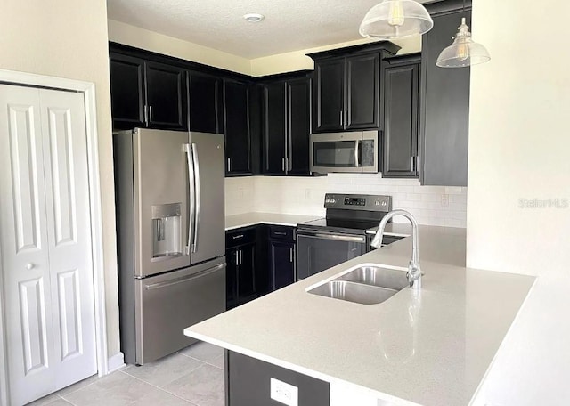 kitchen featuring light tile patterned flooring, sink, decorative light fixtures, appliances with stainless steel finishes, and decorative backsplash