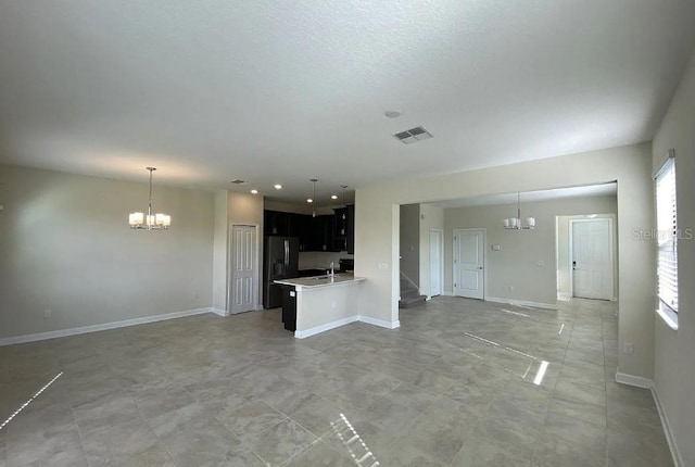 unfurnished living room featuring light tile patterned flooring, sink, and a chandelier