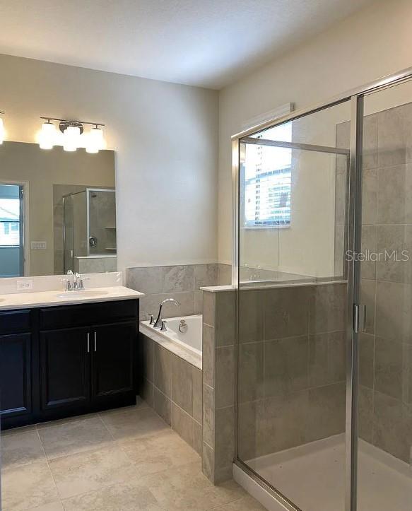 bathroom featuring shower with separate bathtub, vanity, and tile patterned floors