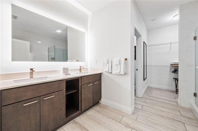 bathroom featuring a shower with shower door and vanity