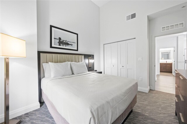 bedroom with a towering ceiling, dark hardwood / wood-style floors, and a closet