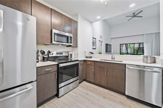 kitchen with vaulted ceiling, sink, ceiling fan, appliances with stainless steel finishes, and light hardwood / wood-style floors