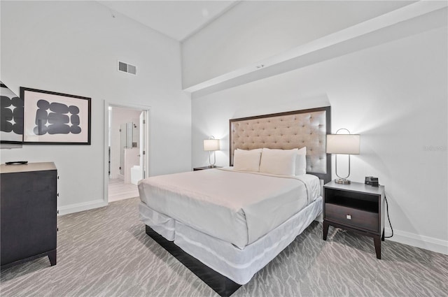 carpeted bedroom featuring ensuite bath and a towering ceiling