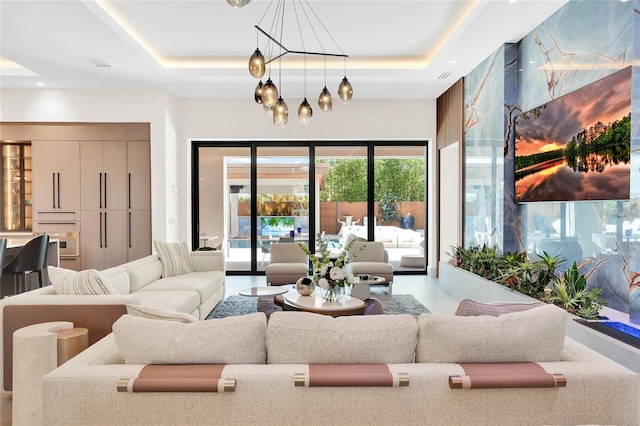 living room featuring a raised ceiling and a notable chandelier