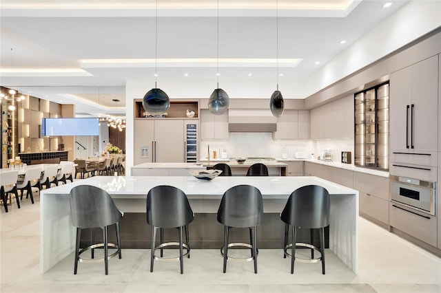 kitchen with a kitchen bar, decorative backsplash, a large island, and stainless steel oven