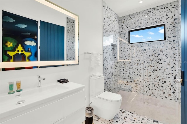 bathroom with tile patterned floors, toilet, a tile shower, and vanity