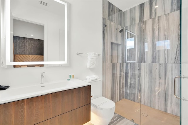 bathroom with vanity, toilet, and a shower with door