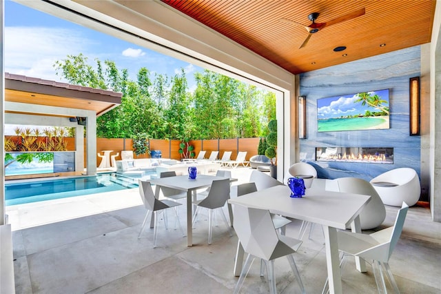 view of patio / terrace with a fenced in pool, ceiling fan, and an outdoor fireplace