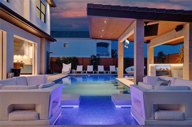 pool at dusk featuring an outdoor living space and a patio area