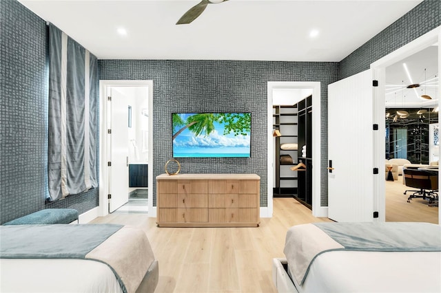 bedroom featuring connected bathroom, ceiling fan, light hardwood / wood-style floors, and a spacious closet