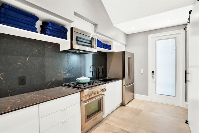 kitchen featuring white cabinets, sink, dark stone countertops, appliances with stainless steel finishes, and tasteful backsplash