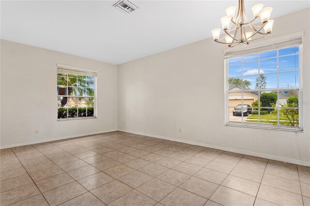 unfurnished room with a chandelier and light tile patterned floors