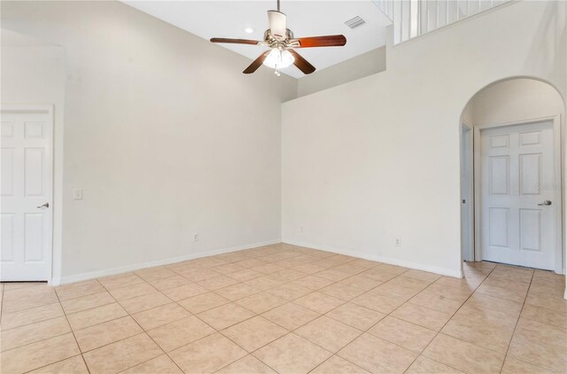 empty room with ceiling fan, a high ceiling, and light tile patterned flooring