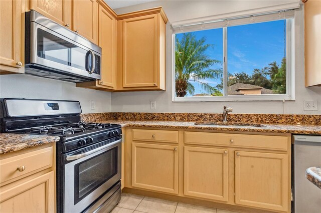 kitchen featuring light stone countertops, stainless steel appliances, sink, and light tile patterned flooring