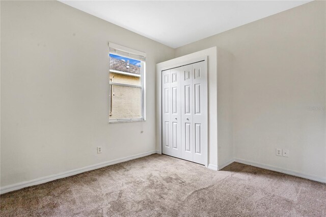 unfurnished bedroom with a closet and light carpet