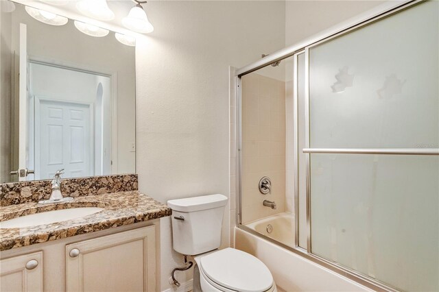 full bathroom with toilet, bath / shower combo with glass door, and vanity