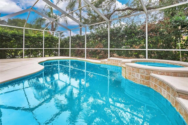 view of swimming pool with glass enclosure, a patio area, and an in ground hot tub