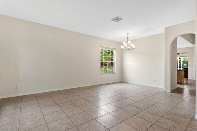 tiled empty room featuring ceiling fan with notable chandelier