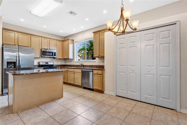 kitchen featuring a kitchen island, appliances with stainless steel finishes, light tile patterned floors, light brown cabinetry, and hanging light fixtures