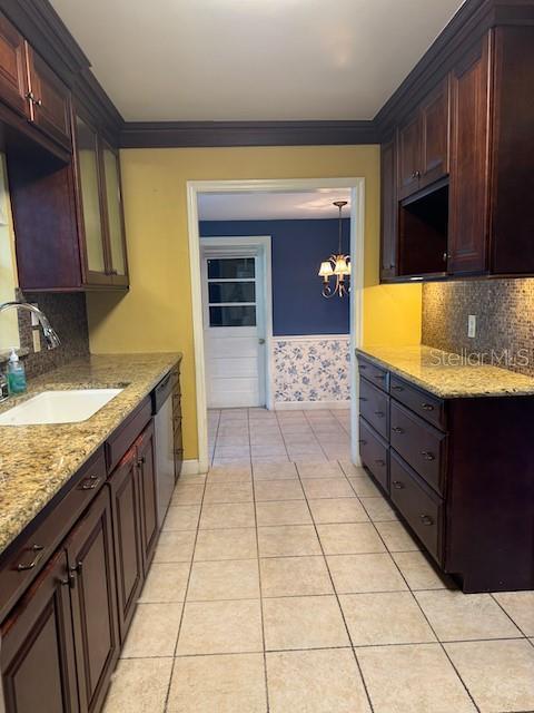 kitchen featuring light tile patterned floors, ornamental molding, and a sink