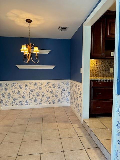 interior space featuring a wainscoted wall, visible vents, an inviting chandelier, light tile patterned flooring, and wallpapered walls