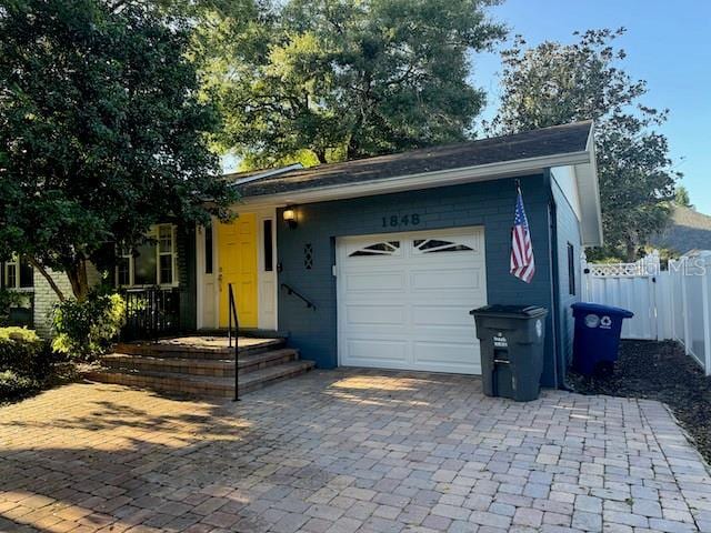 exterior space featuring decorative driveway, fence, and an attached garage