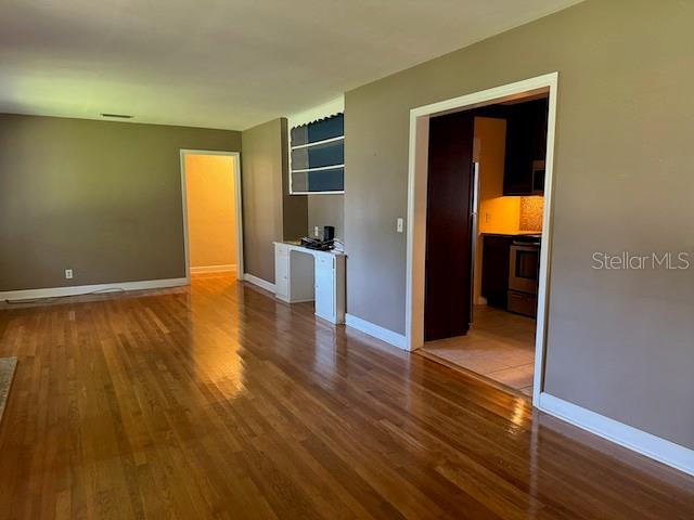 spare room with visible vents, baseboards, and wood finished floors