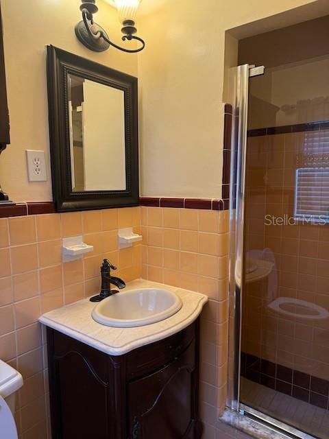 bathroom featuring vanity, a shower with shower door, tile walls, and backsplash