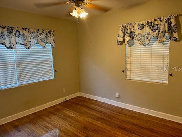 spare room with wood finished floors, a ceiling fan, and baseboards