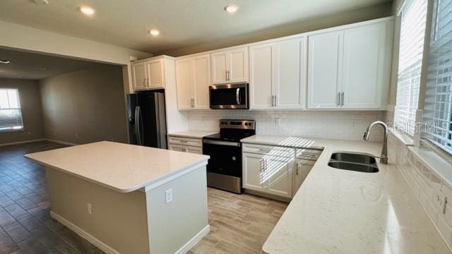 kitchen featuring a kitchen island, sink, decorative backsplash, appliances with stainless steel finishes, and white cabinetry